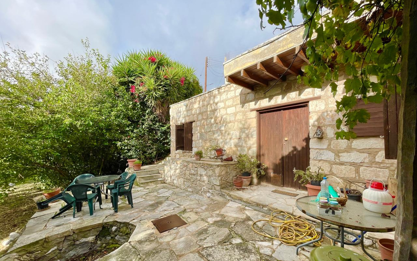 02_Exterior_stone-house-for-sale-paphos-cyprus One-bedroom stone cottage with a fireplace and a beautiful green garden